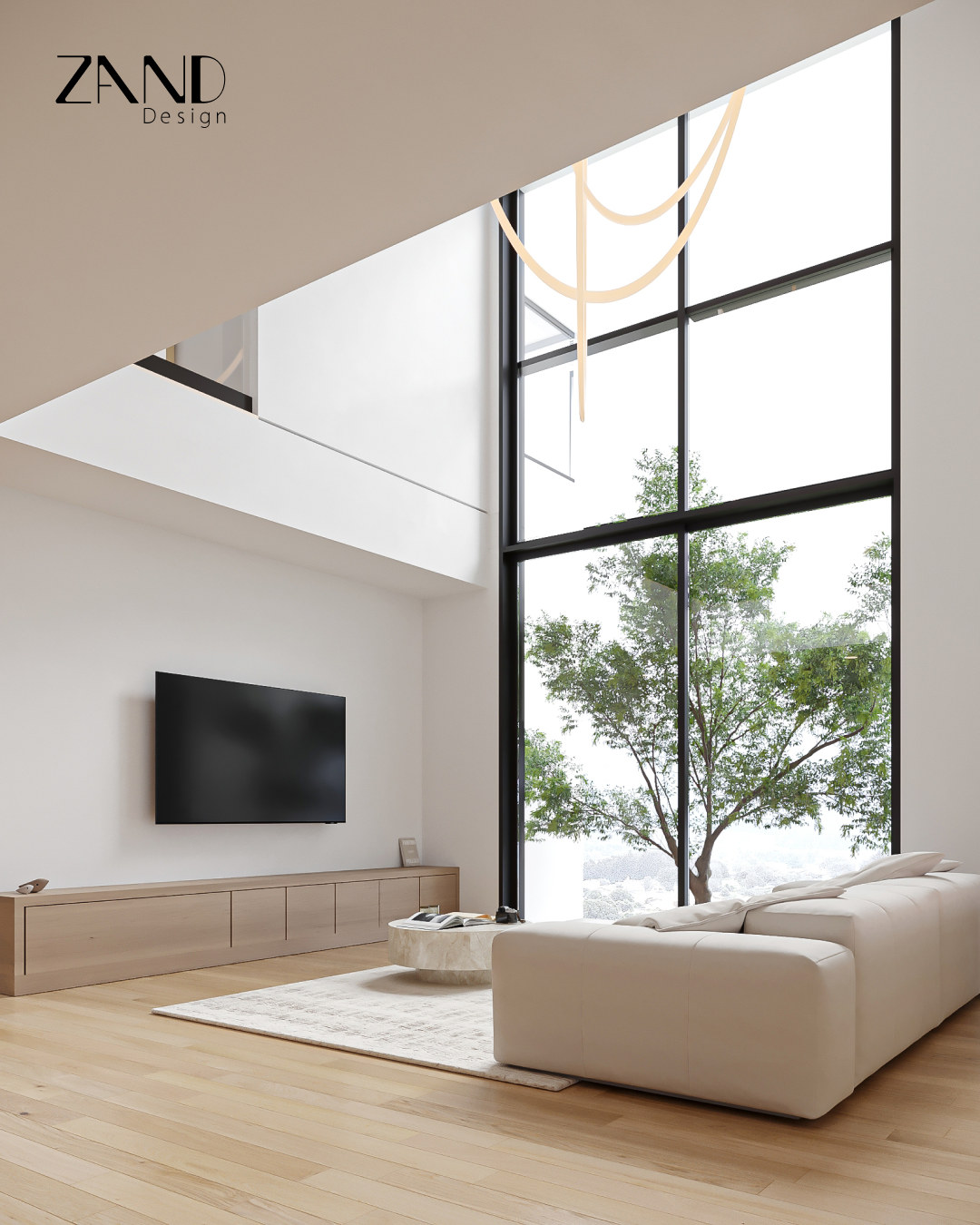 A bright, high-ceilinged living room with a wall-mounted TV over a long wood console. A large floor-to-ceiling window reveals a green tree outside, and a white modular sofa sits on a light rug.